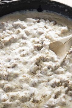 a wooden spoon is in a skillet filled with white sauce and ground meat on the side