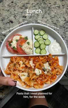 a white plate topped with pasta and veggies next to cucumber slices