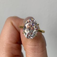 a close up of a person's hand holding a ring with a diamond in it