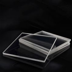 three stacks of clear plastic sheets stacked on top of each other in front of a black background