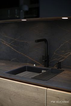 a kitchen sink sitting under a faucet next to a counter top with a wooden cabinet