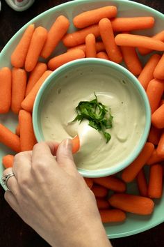 a person dipping sauce into a bowl of carrots with the words quick and easy garlic cashew cream