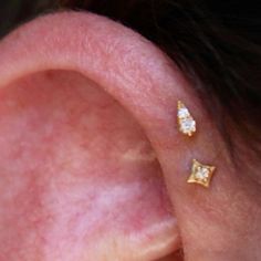 a woman's ear with two small diamond studs