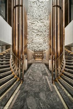 an elegant lobby with marble floors and large metal pillars, surrounded by glass walls that lead to the second floor