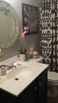 a bathroom with a sink, toilet and shower curtain in black and white color scheme