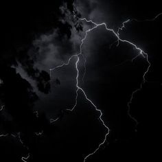 a black and white photo of lightning in the night sky with dark clouds behind it