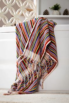 a multicolored towel sitting on the floor next to a bath tub