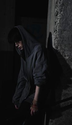 a person in a hoodie leaning against a wall with their hands on the ground