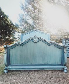 an old blue bed frame sitting on the ground in front of some grass and trees