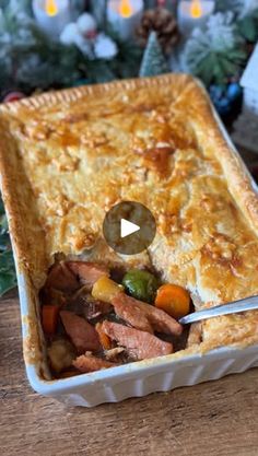 a pie with meat and vegetables in it sitting on a table next to christmas decorations