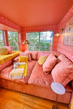 a living room filled with pink couches and pillows