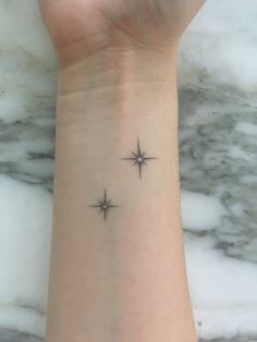 a wrist tattoo with two stars on it