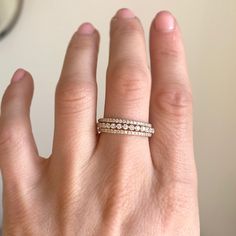 a woman's hand with a wedding band on top of her finger and a mirror in the background