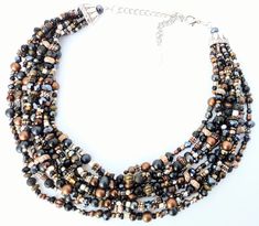 This incredible handmade 8 strand beaded statement necklace is absolutely one-of-a-kind! It is strung on very strong beading wire with a very diverse variety of materials from metal and seed beads, chip and accent beads, to pearls and crystals.  The deep earthy shades of brown, copper, bronze, silver, gold and black, made a wonderful statement piece for absolutely any season of the year!  This piece looks great with business attire, evening wear, or even favorite summer tanks and fall sweaters. A must have for your collection, that you will come back to over and over again.  Measurements: Approximately 17 inches long at the shortest strand, cascading down the neckline to 20 inches at the longest strand with a 3 inch chain extender for easy length adjustment. Please message me for further l Brown Multi-strand Necklace For Party, Unique Multi-strand Necklaces With Spacer Beads, Unique Multi-strand Necklace With Spacer Beads, Brown Multi-strand Beaded Necklaces, Elegant Multi-strand Brown Beads, Elegant Brown Multi-strand Beads, Artisan Brown Multi-strand Beaded Necklace, Artisan Multi-strand Brown Beads, Unique Brown Multi-strand Necklace