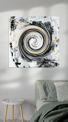 an abstract painting hangs on the wall above a bed