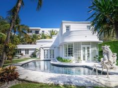 a house with a pool in front of it and palm trees around the pool area