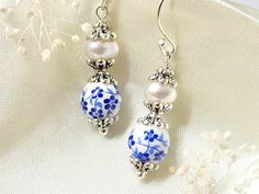 Tiny blue flowers, adorn these dainty porcelain earrings. They feature genuine freshwater pearls, that are embellished with antique silver bead caps. These elegant earrings, will make a lovely addition to your jewelry collection!   Please note that each natural pearl will vary slightly in shape and number of striations, making each piece one of a kind! I always try to choose pearls that closely match each other, and look as close to the pictures as possible.  Product details: * Silver plated ear Blue And White Earrings, Victorian Earrings, Porcelain Earrings, Earrings Flower, Silver Dangle Earrings, Earrings Pearl, Natural Pearl, Silver Bead, Earrings Blue