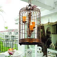 a birdcage filled with candles sitting on top of a table next to a window