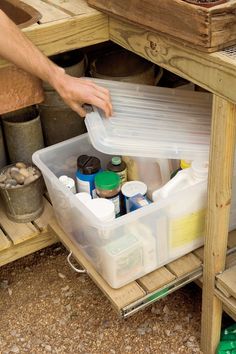 a person is picking up plastic containers from the shelf on top of a wooden table