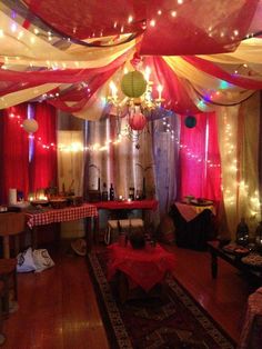 a room filled with lots of red and white drapes covered in lights next to a table