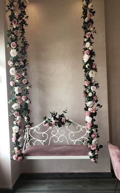 a bed with pink and white flowers hanging from it's sides next to a wall