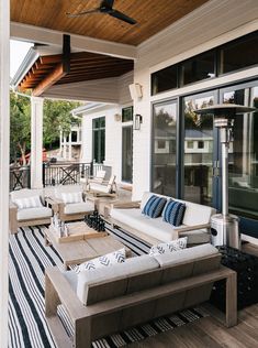 an outdoor living area with couches, tables and ceiling fan on the deck outside