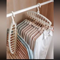 a rack with clothes hanging on it in front of a closet full of folded shirts