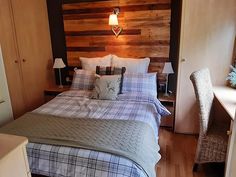 a bed sitting in a bedroom next to a wooden headboard and table with two lamps on it