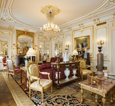 an ornate living room with chandelier and chairs