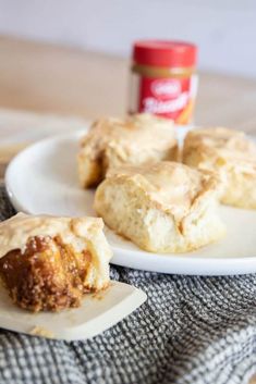 some biscuits are sitting on a plate with a jar of peanut butter in the background