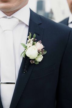 a man wearing a suit and tie with flowers on it's lapel pin