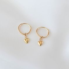 Sweet and cute, these are a pair of small huggie earrings with a dangling gold heart charm. All materials are 14K gold filled and are tarnish-resistant, water-resistant, and hypoallergenic. Hoop measures 12mm in diameter while the heart measures 4 mm in diameter. The heart charm is single sided with a hollow back which makes it very lightweight and comfortable for everyday wear. To put them on, don't pull the hoop apart, instead bend them towards opposite sides like shown in the photo. Happy sho Gift Dangle Cartilage Earrings, Cute Sterling Silver Hoop Earrings For Pierced Ears, Everyday Handmade Huggie Earrings, 14k Gold Filled Small Hoop Earrings As Gift, Small Hoop 14k Gold Filled Earrings For Gift, Gift Small Hoop Huggie Earrings 14k Gold Filled, Dainty Hypoallergenic Hoop Heart Earrings, Gift Small Hoop Earrings 14k Gold Filled, Huggie Cartilage Earrings As Gift