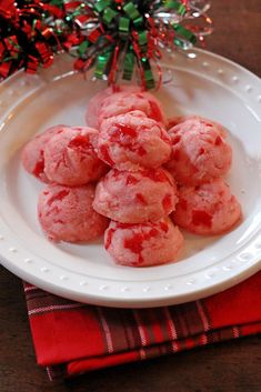 a white plate topped with red cookies next to a christmas tree