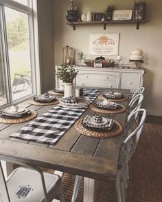 a dining room table with place settings and plates on it, in front of a window