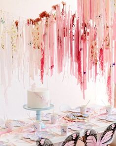 a table topped with a cake covered in pink icing next to a butterfly decoration