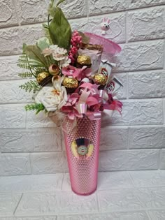 a pink vase filled with candy and flowers