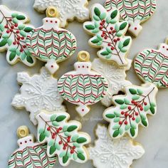 decorated christmas cookies on a table with holly leaves and mistle berries in the center