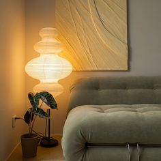 a living room with a couch, table lamp and potted plant in the corner