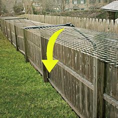 a wooden fence with a yellow arrow pointing to the right and an old house in the background