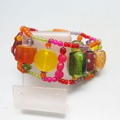 This lovely detailed citrusy colored bead southwestern bracelet dates to the 1980s. It  measures  1 3/8ths inches tall .  It is a comfortable fit on my 7 1/4 inch wrist with lots of stretch left.    I don't see any maker's markings. It is in excellent condition. This will arrive in a lovely gift box for stellar gift giving or safe storage. For more vintage jewelry of all kinds, kindly check out my Etsy store at  www.etsy.com/shop/PandPF Retro Adjustable Jewelry With Colorful Beads, Adjustable Retro Jewelry With Colorful Beads, Vintage Adjustable Bracelets With Colorful Beads, Bohemian Stretch Bracelet With Colorful Beads, Vintage Multicolor Beaded Bracelets For Festival, Bohemian Yellow Stretch Bracelet With Large Beads, Bohemian Orange Stretch Bracelet With Colorful Beads, Vintage Multicolor Bracelets With Large Beads, Vibrant Adjustable Yellow Beaded Bracelets