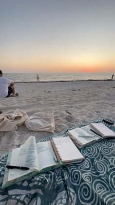 a man sitting on top of a beach next to an open book