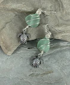 These  genuine Sea Glass Errings with Turtle Charm are fun! They are a beautiful light seafoam green color and have a small silver Sea Turtle Charm dangling from the bottom. These earrings are handmade from genuine surf tumbled Sea Glass.  I chose to enhance these cute earrings with a silver wire wrap design.  They are lightweight and perfect for daily wear.  These earrings are simply stunning and will definitely get you compliments whenever you wear them.  Because these are natural surf Tumbled Green Dangle Jewelry For The Beach, Ocean-inspired Green Jewelry For Vacation, Green Ocean-inspired Jewelry For Vacation, Handmade Sea Glass Green Earrings, Green Sea Glass Earrings With Ear Wire, Handmade Green Jewelry For Vacation, Green Jewelry With Matching Earrings For The Beach, Green Sea Glass Earrings For Gift, Green Dangle Jewelry For Vacation