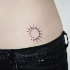 a woman's stomach with a small sun tattoo on it