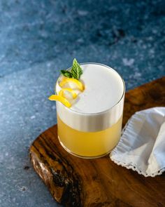 a drink with lemon and mint garnish sitting on a wooden tray