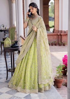 Pakistani Bridal Dress in Green Lehenga Choli Style is an embellished attire adorned with lavish designs and ornaments. Premium quality fabric and perfect stitching make this beautiful Lehenga Dress an epitome of beauty and your priority for the wedding. Lehenga Choli: The beautiful choli in alluring parrot green shade is fully adorned with hand-crafted details of sequins, pearls, stones, beads, zardosi, and embroidery. The lavish contrast of blue, pink, and goldwork make this choli a perfect choice to pair with Lehenga and wear on your wedding. Green Lehenga: The Bridal Lehenga has premium quality net fabric and it looks perfect when paired with the heavily embellished choli. The Lehenga has a huge flare and is adorned with beads, stones, threads, and embellished borders, giving a flawles Choli Dupatta Style, Green Pakistani Bridal Dress, Choli Style, Bridal Lehenga Pakistani, Pakistani Bridal Lehenga, Green Lehenga Choli, Pakistani Bridal Dress, Dupatta Style, Bridal Dupatta