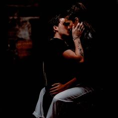 a man and woman kissing in the dark with their hands on each other's shoulders