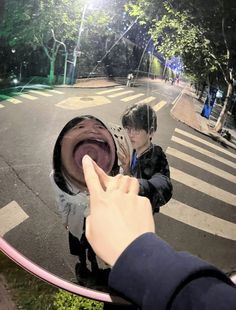 two people standing in front of a mirror with one pointing at the other person's hand