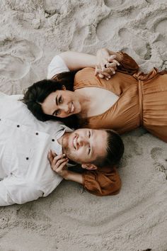 a man and woman laying in the sand together