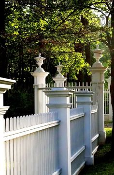 a white picket fence with trees in the background