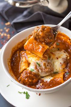 a white bowl filled with meat and cheese covered in sauce on top of a plate